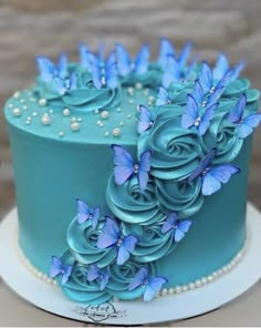 there is a blue cake with flowers on the top and pearls around the edges,