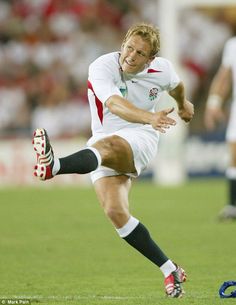 a man kicking a soccer ball on top of a field