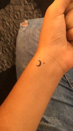 a person's arm with a small crescent tattoo on the left side of their wrist