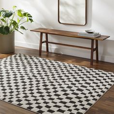 a black and white area rug in front of a wooden table with a mirror on it