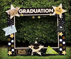 a graduation photo frame is decorated with stars and confetti on the grass in front of a hedge