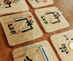 four cork coasters with different types of letters and numbers on them sitting on a wooden table