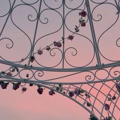 an iron structure with flowers growing on it's sides and the sky in the background