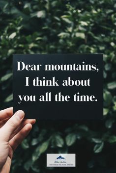 someone holding up a sign that says dear mountains, i think about you all the time