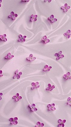 purple flowers floating in the water on top of a pink surface with white swirls