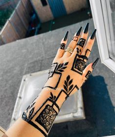 a woman's hand with black and white tattoos on it, next to a window