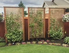 a wooden fence surrounded by flowers and greenery in a backyard area with green grass