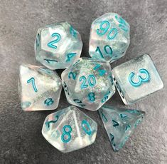 six clear and blue dice with numbers on the sides, sitting on a gray surface