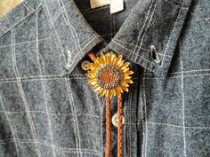 a denim shirt with a sunflower brooch attached to the front and back buttons