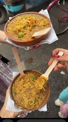 two people holding bowls of food with spoons