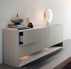 a white cabinet with some books and vases on top of it in a room