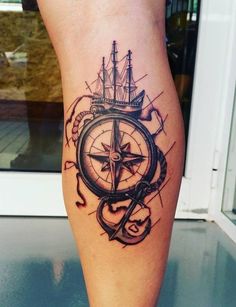 a compass tattoo on the leg of a woman's legs, with an anchor and ship