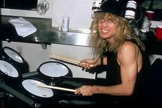 a man with long hair playing drums in a kitchen