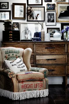 a chair sitting in front of a dresser with pictures on the wall