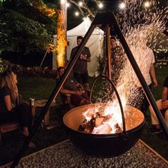 people sitting around an open fire pit with water spewing out from the top