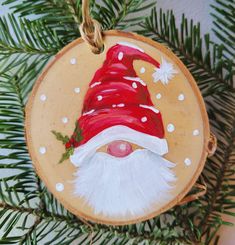 a wooden ornament with a santa clause hat on it's face hanging from a christmas tree