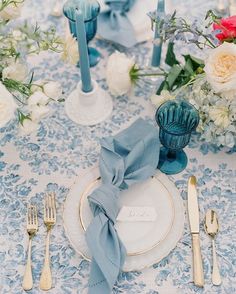 the table is set with silverware and blue napkins