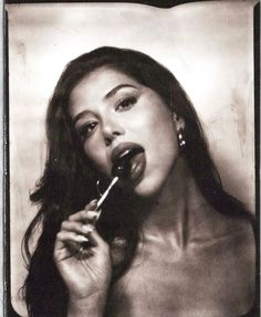 a black and white photo of a woman holding a toothbrush in her mouth while brushing her teeth