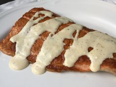 a piece of meat covered in gravy on top of a white plate with a fork