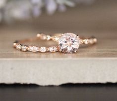 a close up of a diamond ring on a wooden surface with flowers in the background