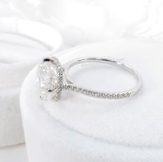 a white diamond ring sitting on top of a pillow