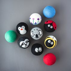 several balls with painted faces are arranged in a circle on a gray surface and one is red, the other blue