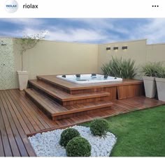 a hot tub sitting on top of a wooden deck next to a planter filled with potted plants