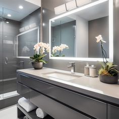 a bathroom with a large mirror, sink and flowers in the vase on the counter