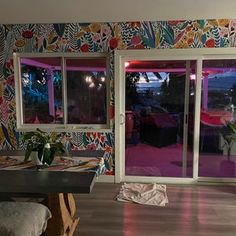 a living room filled with furniture and colorful wall paper on the walls next to sliding glass doors