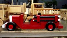 a red toy fire truck sitting on top of a wooden table next to other toys