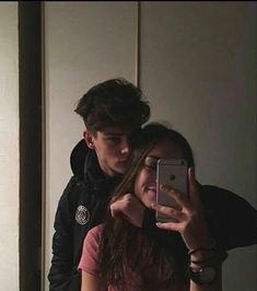 a young man and woman taking a selfie in the mirror with their cell phone