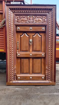 a large wooden door sitting on top of a cement floor next to a red truck