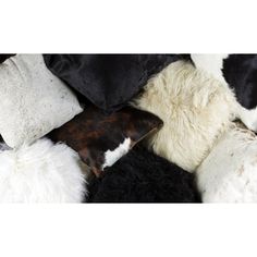 a pile of black and white pillows with different colored furs on top of them