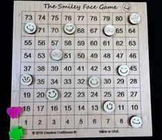 a wooden board game with smiley faces on it and numbers arranged in rows to spell out the word smiley face game