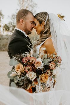 a bride and groom standing together in the desert