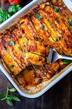 a casserole dish with zucchini and spinach in it on a wooden table