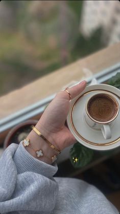 a woman holding a cup of coffee in her hand