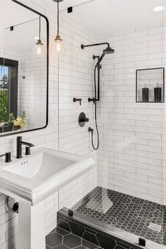 a black and white tiled bathroom with a sink, shower head, mirror and tile floor