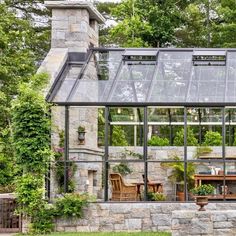 a stone house with glass walls and lots of greenery