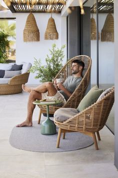 a man sitting in a wicker chair on top of a patio