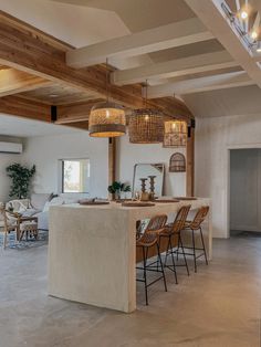 a large open kitchen and dining room with wooden beams on the ceiling, along with modern chairs