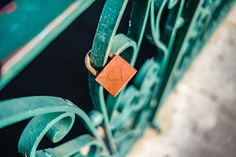 an orange padlock attached to a green metal bench with rusted ironwork on it