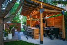 an outdoor bbq with lights and grilling area in the back yard, surrounded by trees