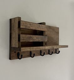 a wooden shelf with three hooks on it