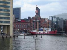 there is a large red boat that is in the water near some buildings and people