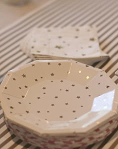 two white plates sitting on top of a striped tablecloth covered table with gold stars