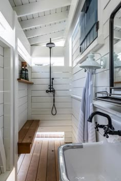 a bathroom with white walls and wood flooring next to a bathtub, shower head, and sink