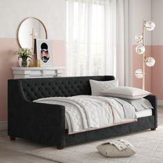 a bedroom with pink and white walls, a gray daybed and a mirror on the wall