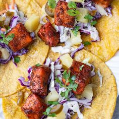 three fish tacos with cole slaw and pineapple salsa on top, sitting on a white plate