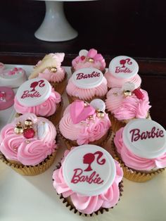 cupcakes with pink frosting and white icing are arranged on a table